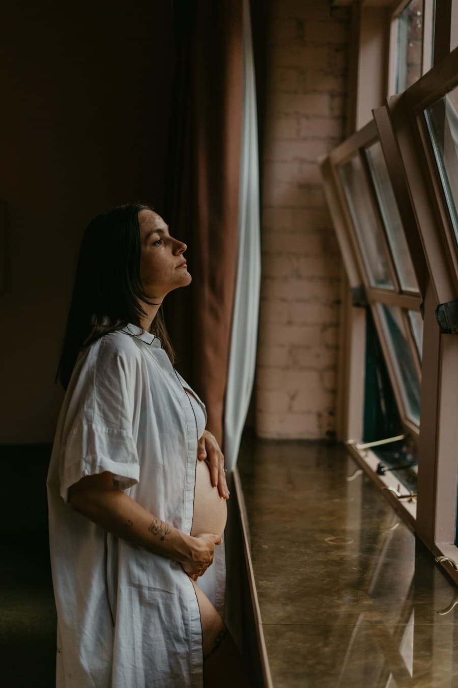 A pregnant woman standing by a window