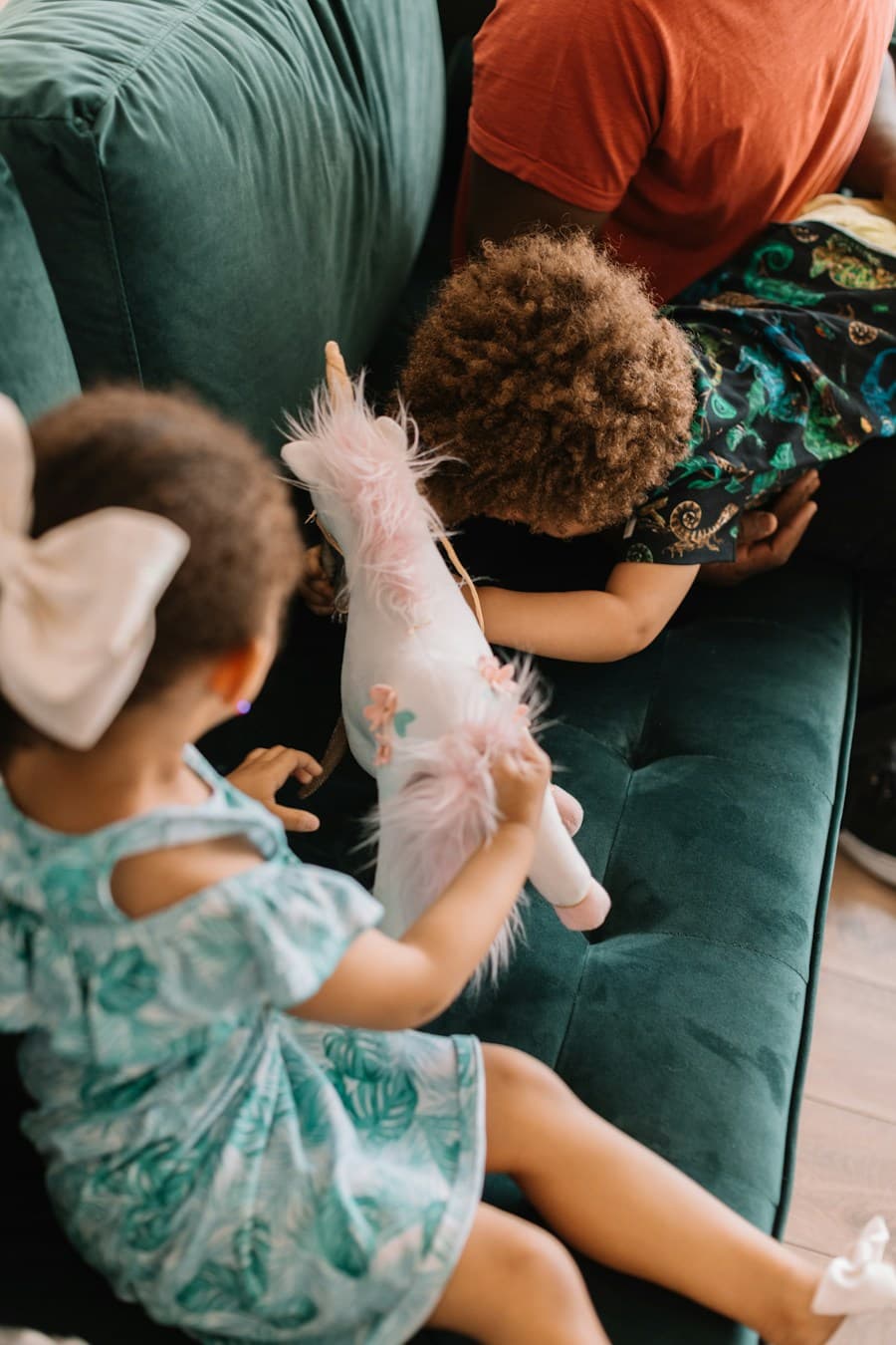Two children playing on a sofa with an adult