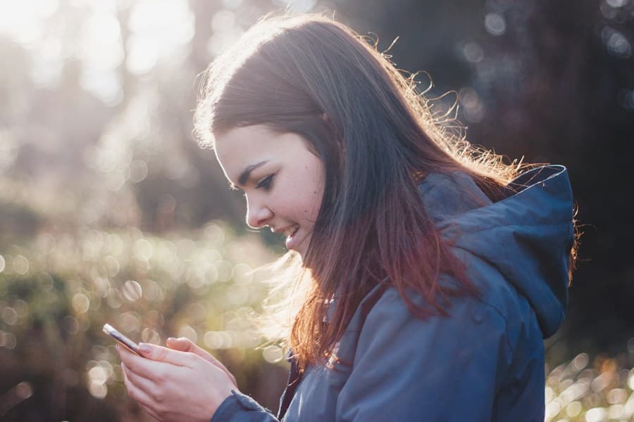 A woman smiling at her phone in the sun